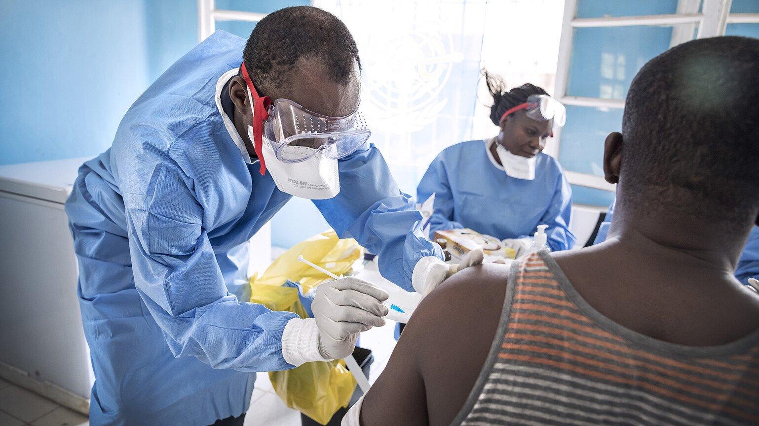 Doctor vaccinates a patient in the company of a nurse.