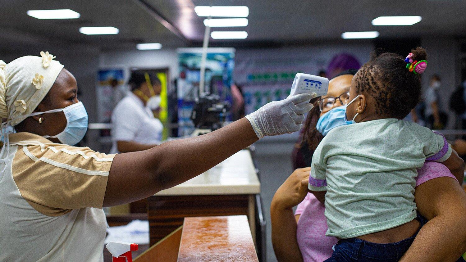 A mother and child's body temperatures are being tested at the gate of entry upon arrival at the Murtala International Airport in Lagos.
