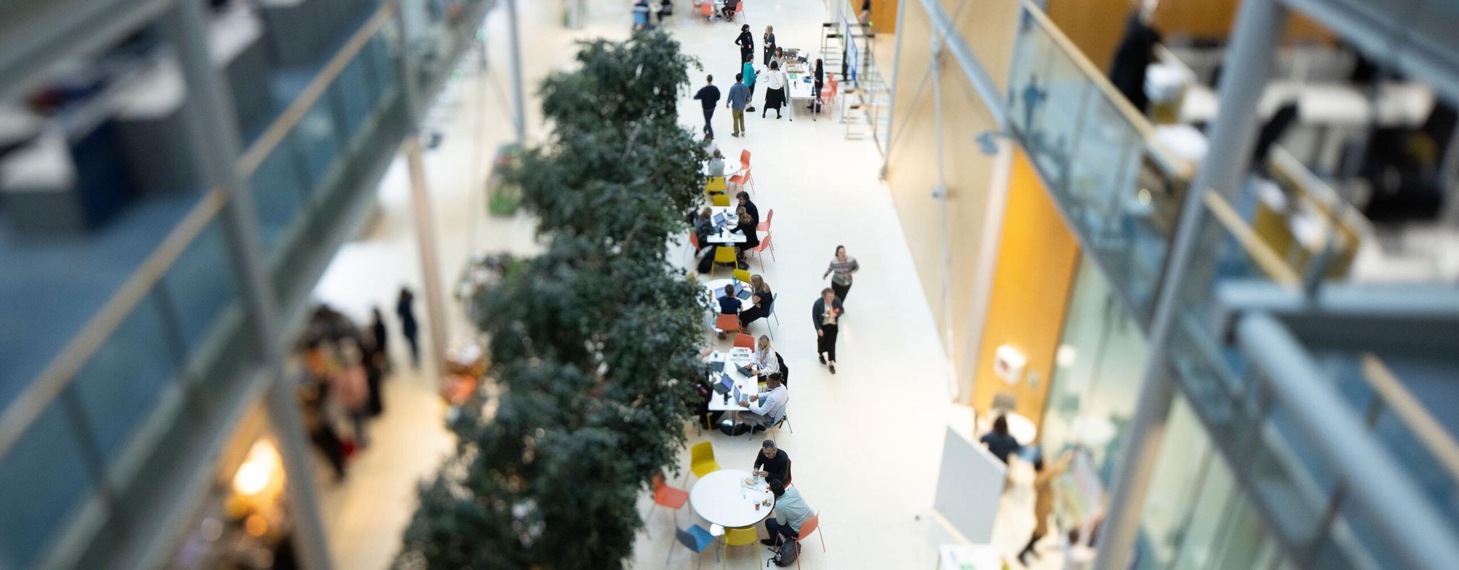 Aerial view of Wellcome staff sitting at tables and walking along the office ground floor.