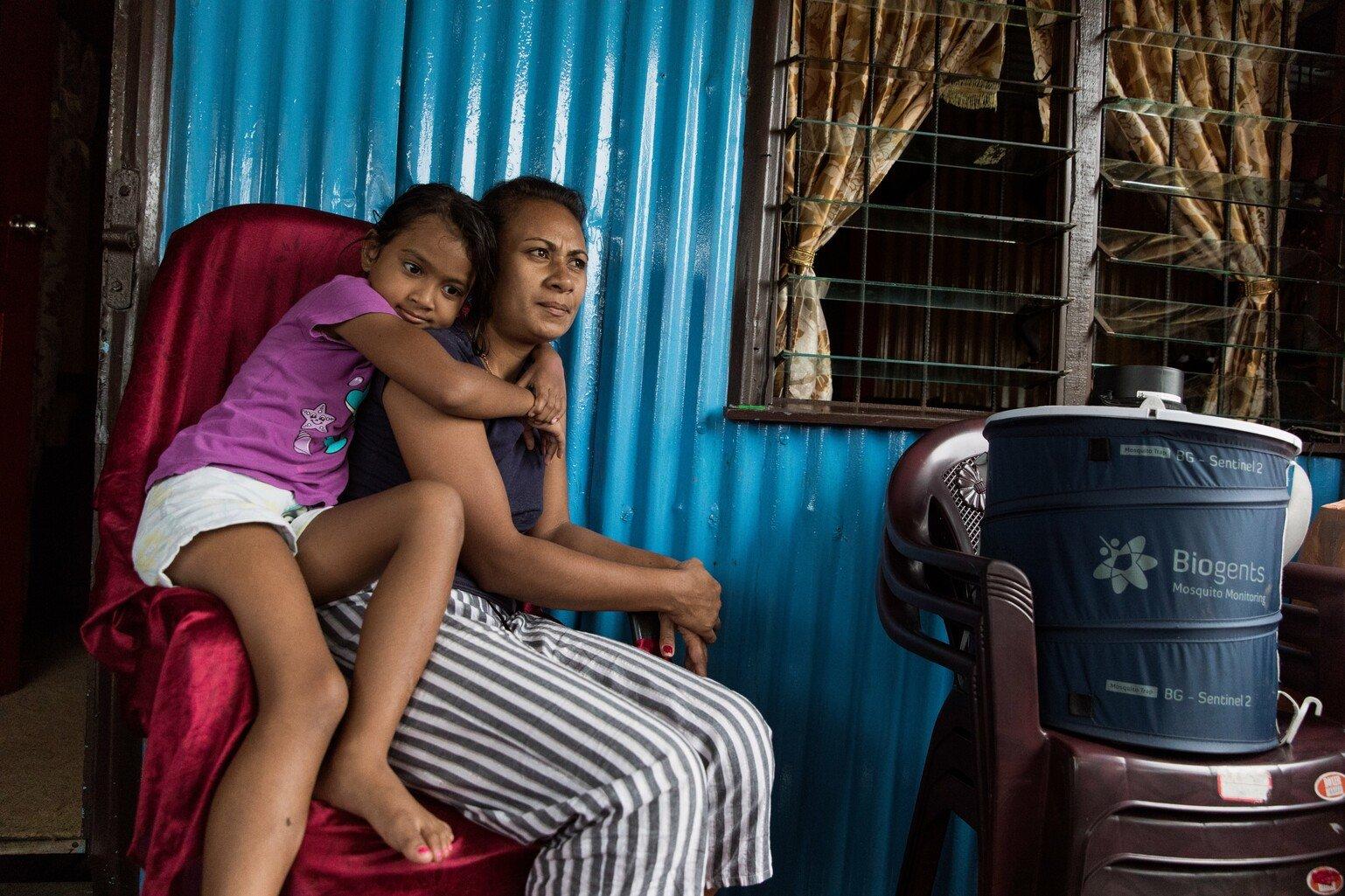 Mother and daughter sitting by their mosquito trap