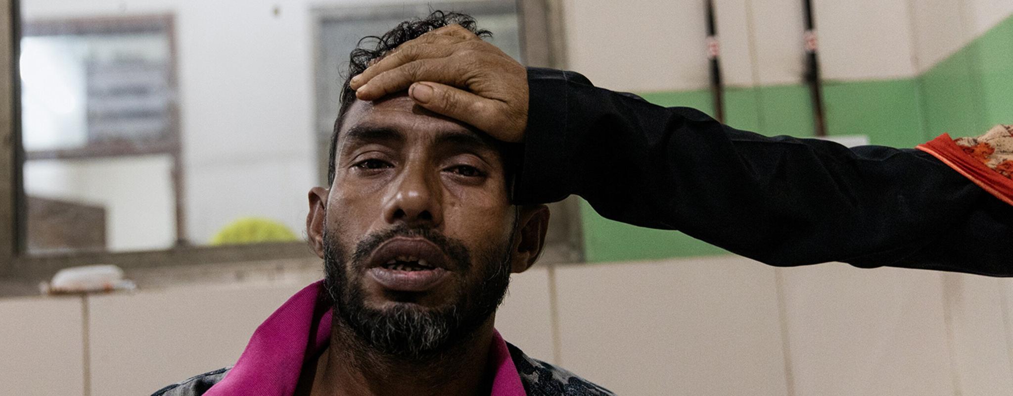 Man with suspected dengue fever sitting on a bed at Dhaka Medical Hospital