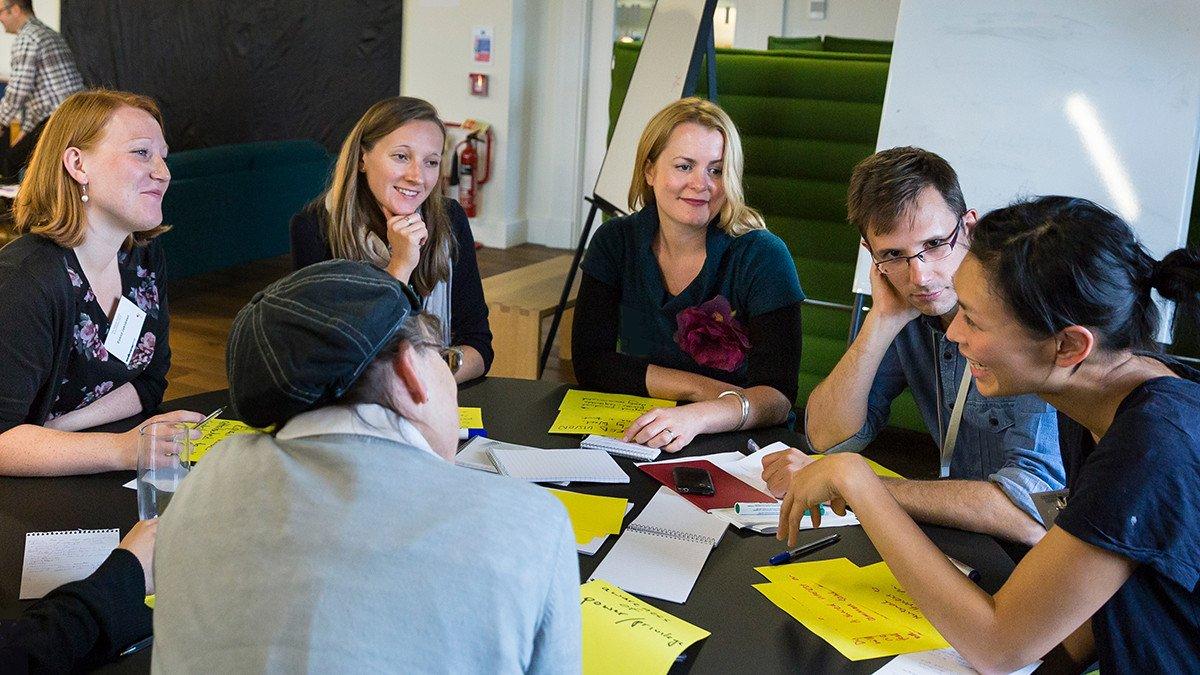 Six researchers have a discussion around a table