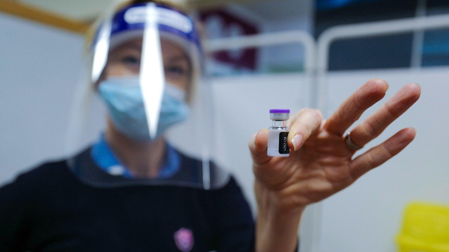 A healthcare worker holds up a dose of a Covid-19 vaccine.