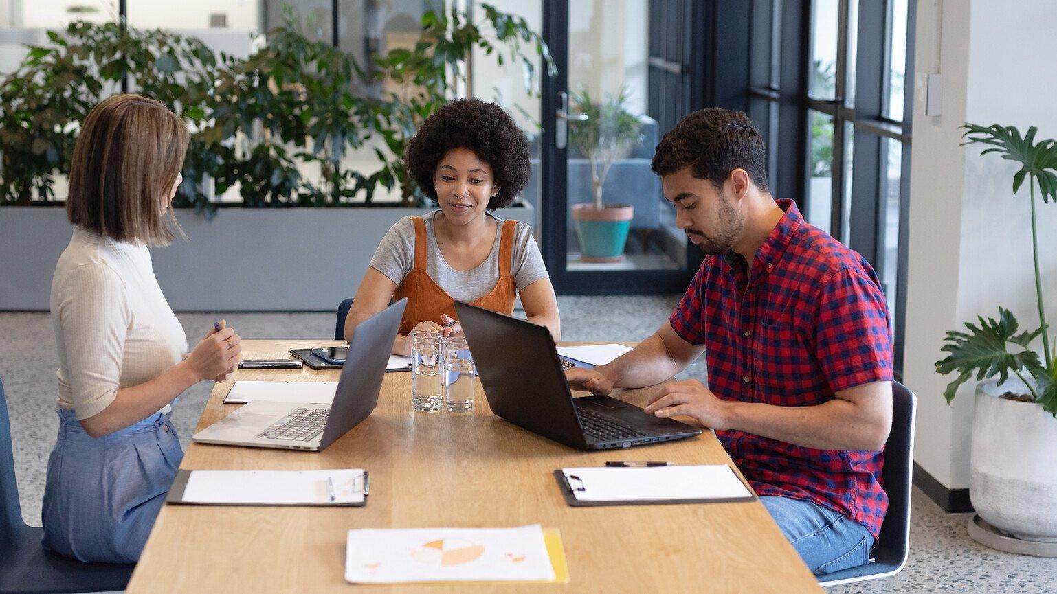 Three young people sitting and discussing work in an office.