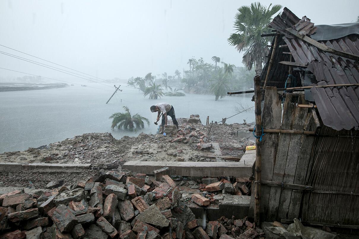 Habibur Rahman Sarder salvages anything still useful from the wreckage of his house, which was hit by a hurricane.