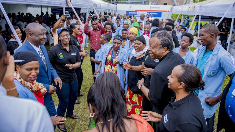 A group of health officials and health workers at a community event, surrounded by photographers.