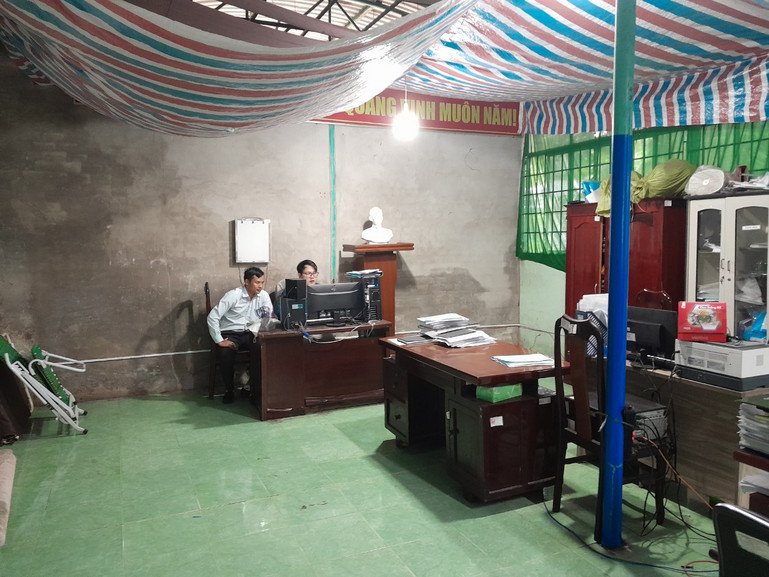 People in an office space looking at a computer. There are desks and cabinets in the room.