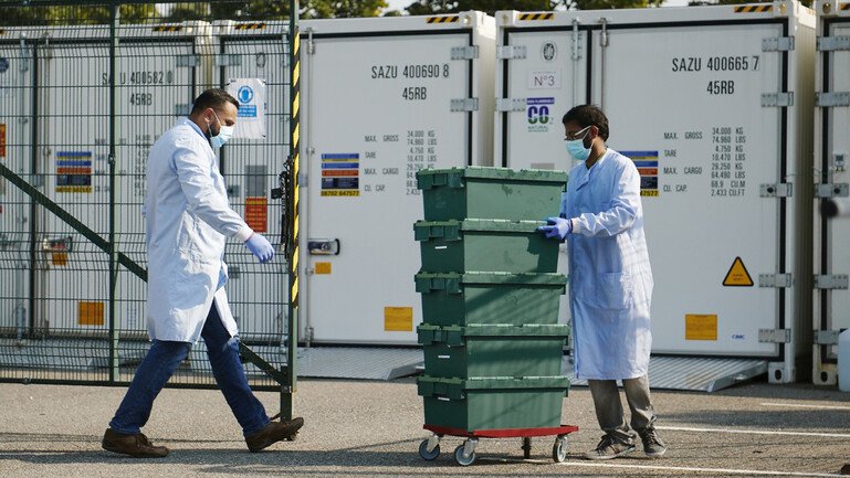 Two scientists are wheeling a stack of boxes with Covid-19 tests.