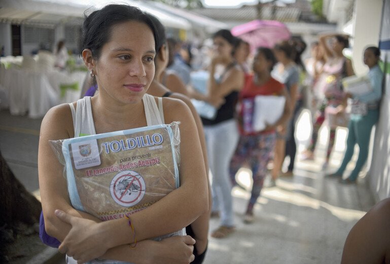 A pregnant woman holds a mosquito net.