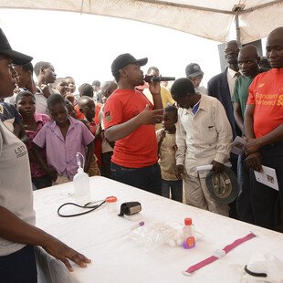 People gather around a table with medical equipment