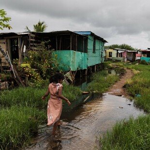 Woman walking behind her house in Nanuku settlement