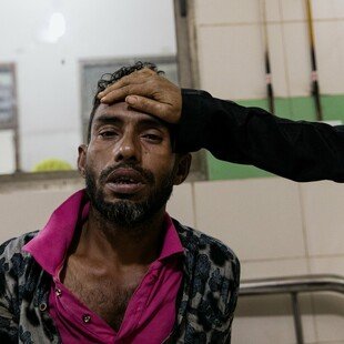 Man with suspected dengue fever sitting on a bed at Dhaka Medical Hospital