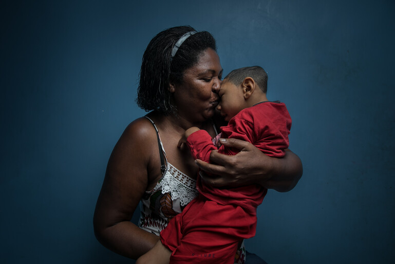 Small boy with microcephaly being cuddled by the woman who adopted him