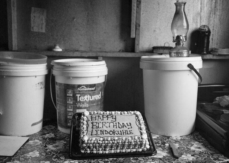 A birthday cake in front of plastic buckets