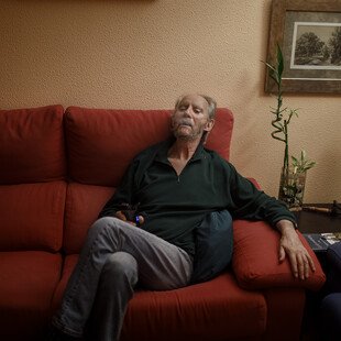 A man sits on a sofa holding a tv remote control