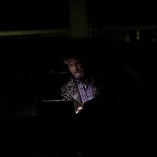 A man sits in his car in his garage