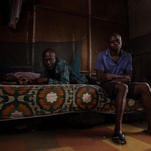 Two residents sit on their bed, raised up on tyres to try to keep it out of the water