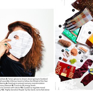 Portrait of a young woman next to the items in her mental health kit - glitter cushion, tartan gloves, wood burner, wiccan book, socks, earplugs, tea, cocoa, pinecones, crystals, chocolate, philosophy book