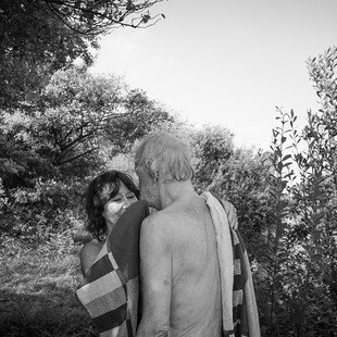 A woman wraps a man in a towel after bathing