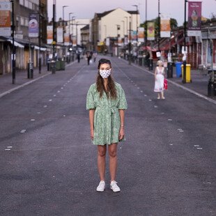 A portrait of a masked pedestrian on London's Ridley Road.