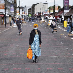 A portrait of a masked pedestrian on London's Ridley Road.