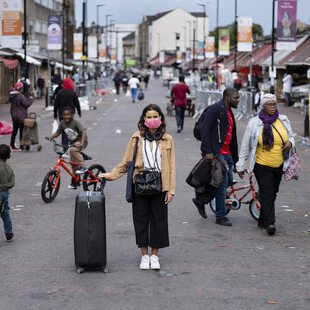 A portrait of a masked pedestrian on London's Ridley Road.