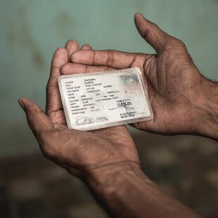 A trans woman holds ID card, which has her old name on it.