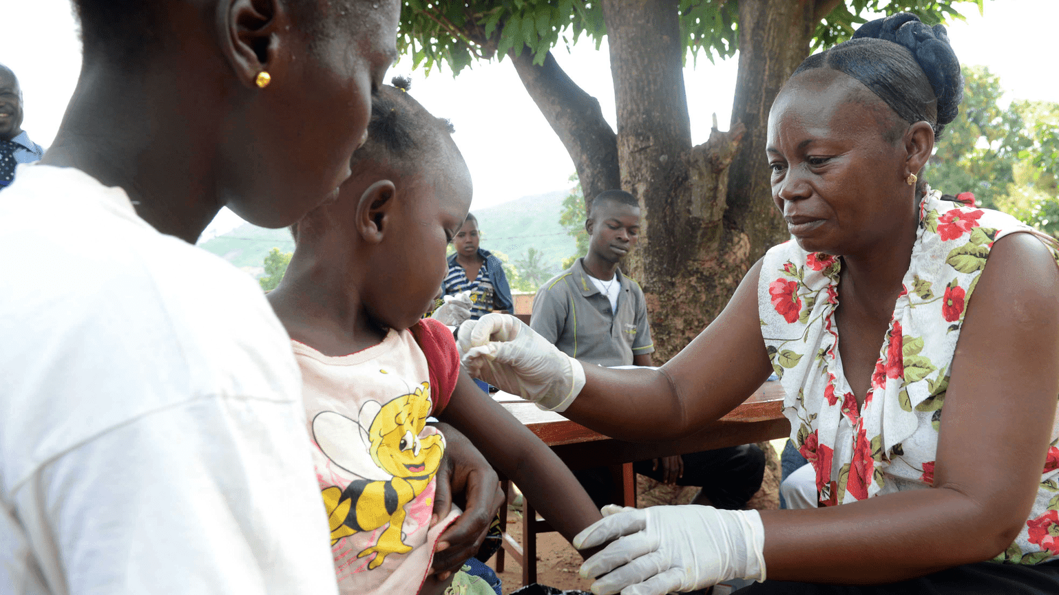 A girl gets a vaccination against measles from a health worker 